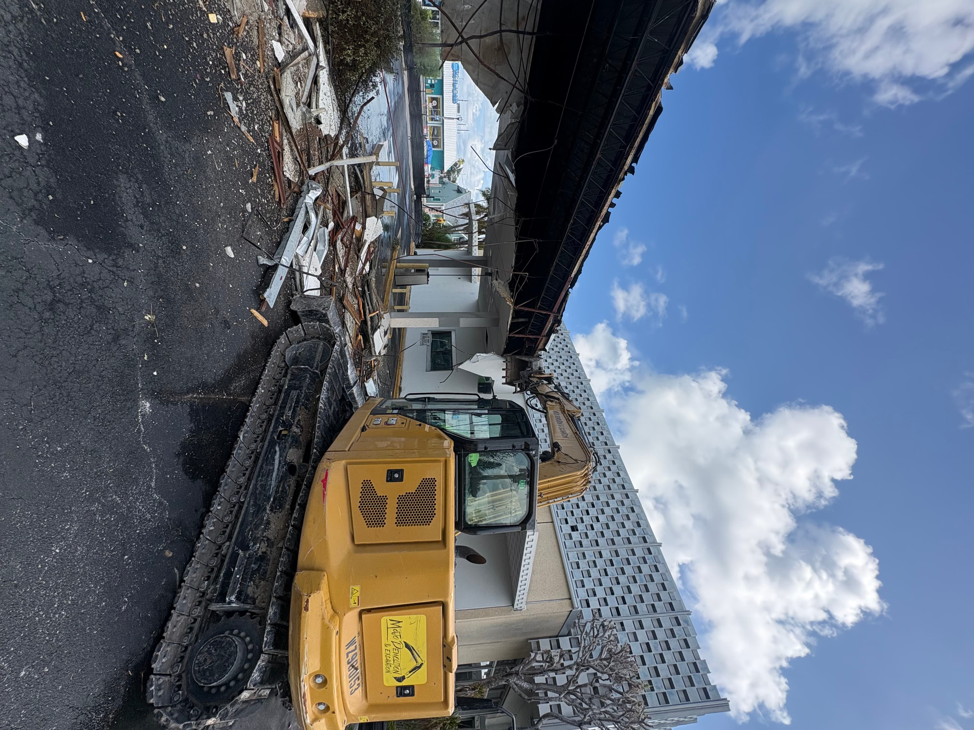 Mojo demolition equipment clearing debris outside a commercial building