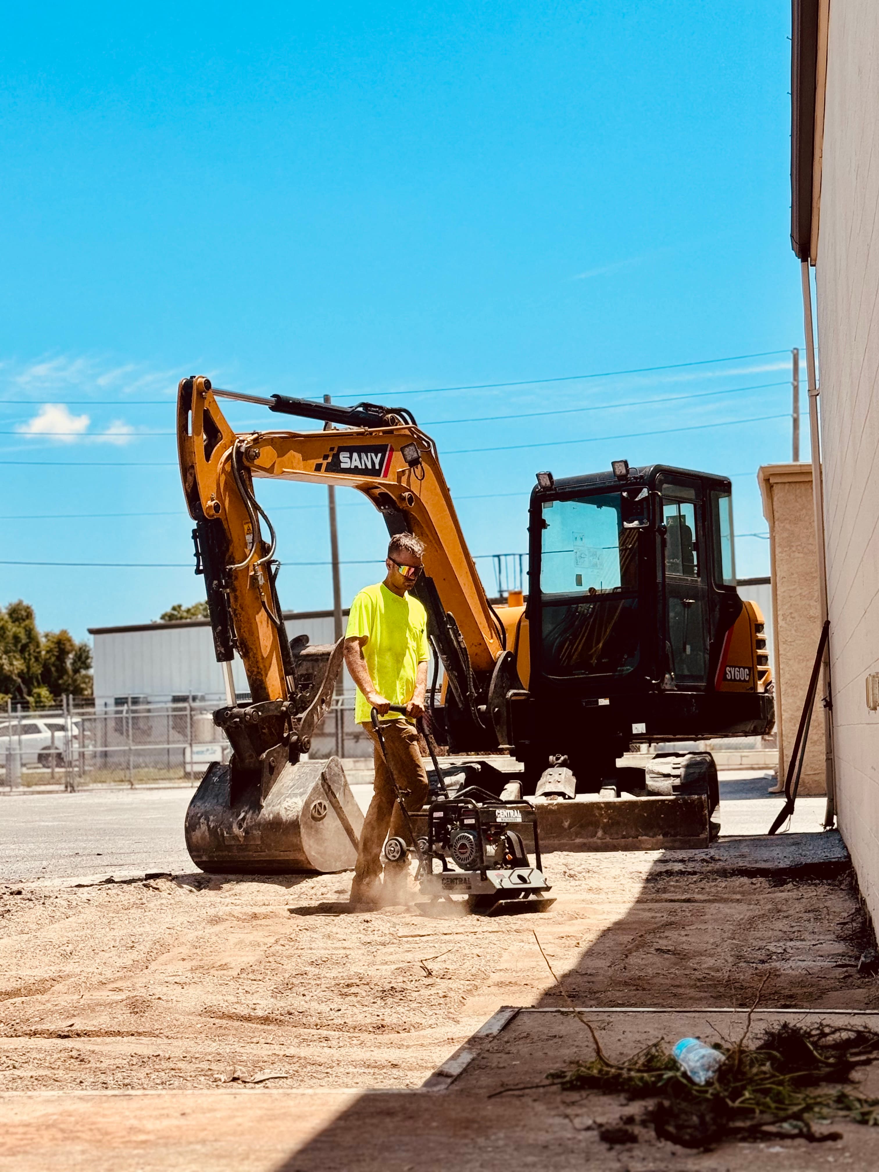Mojo crew member compacting dirt beside excavation equipment